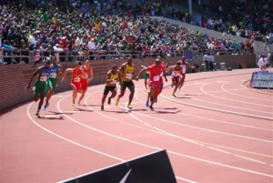 men racing in a relay with a jampacked stadium